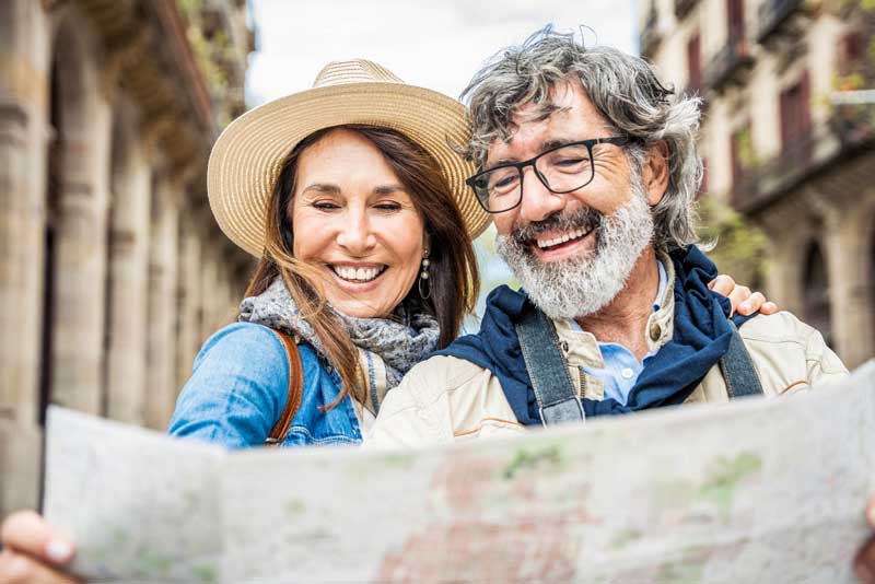 Image of a mature couple smiling and reading a map.